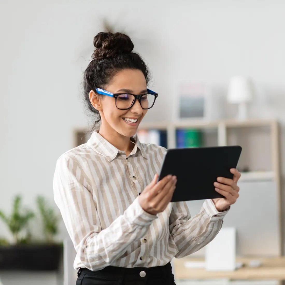 Smiling analyst in glasses reviewing a tablet at the office