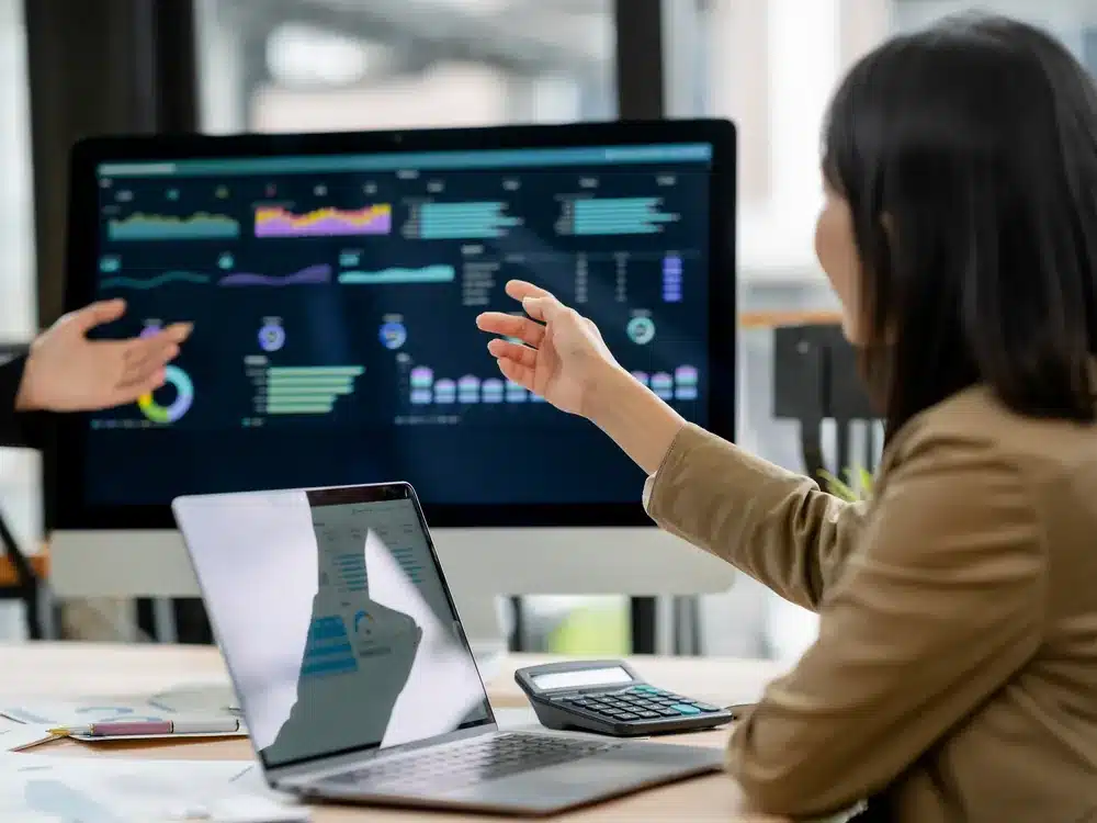 Marketing analyst reviewing data charts on monitors for AI citation and brand mention monitoring