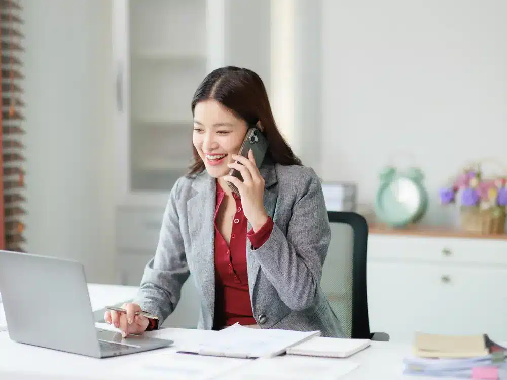 Businesswoman on the phone while typing at a white desk, a fit for flexible marketing add-ons
