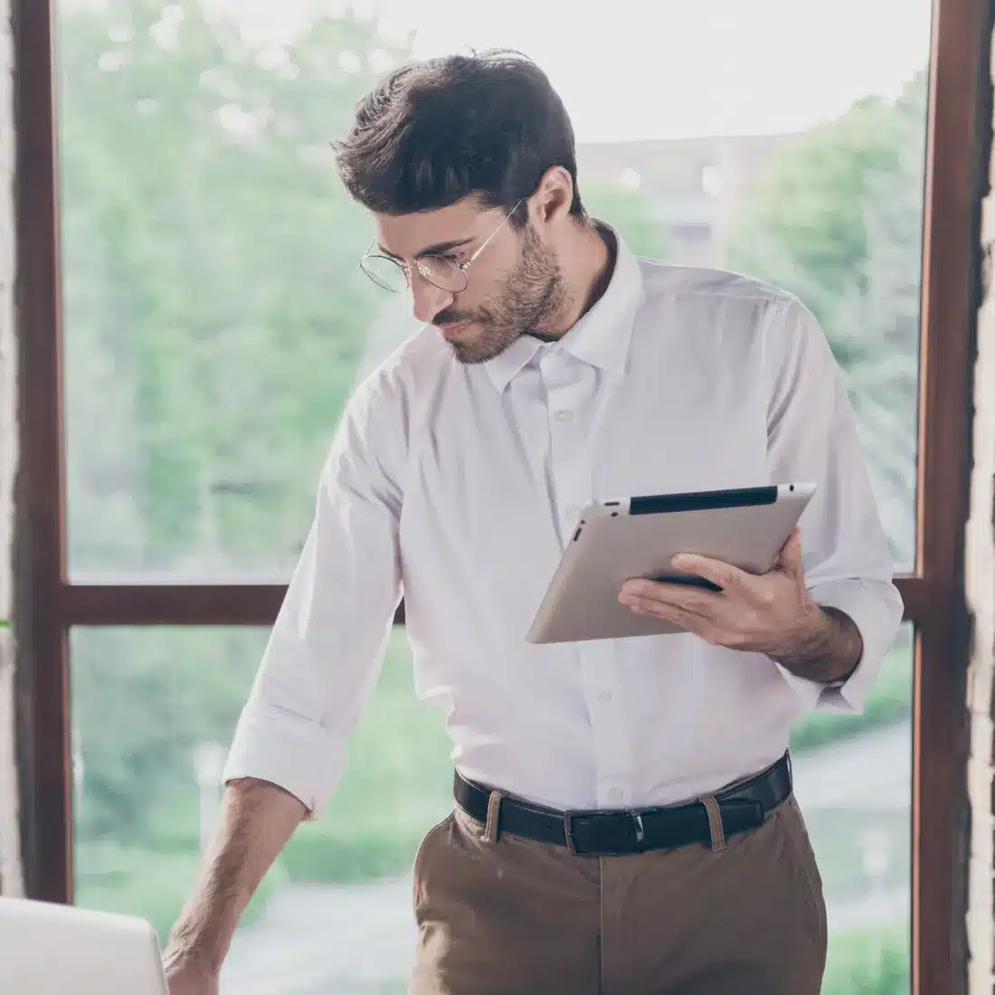 Consultant reviewing a tablet by an office window