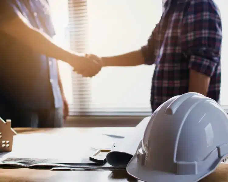 Contractor handshake beside a hard hat