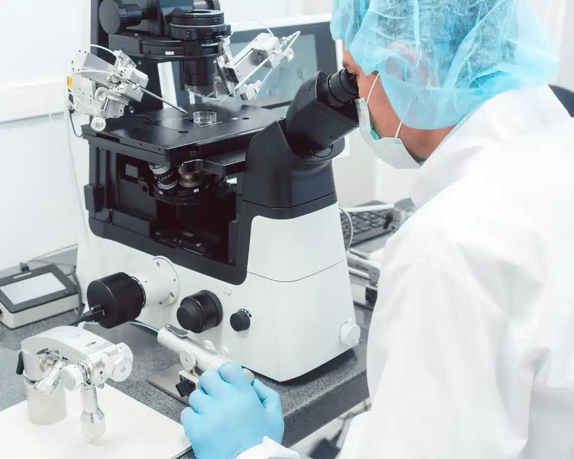 Clinician working at a microscope in a clean fertility lab