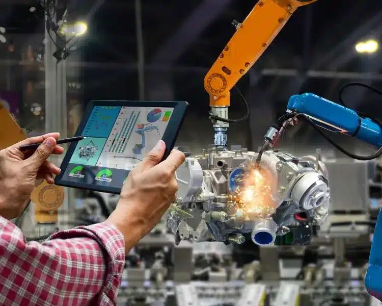 Engineer using a tablet beside a robotic arm