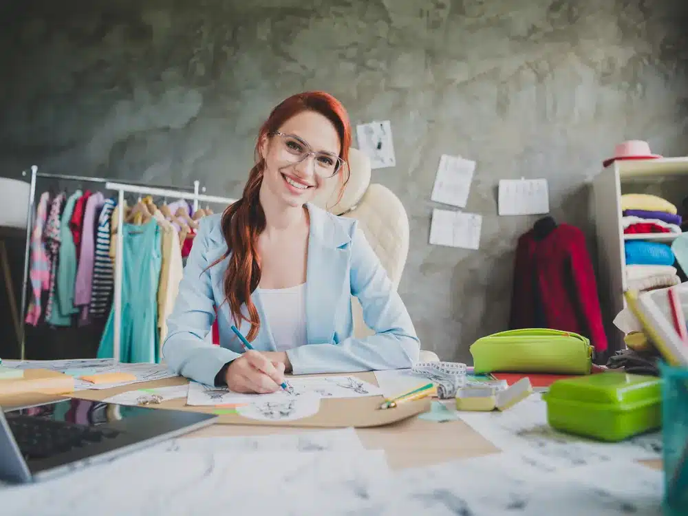 Branding Packages | CICOR Marketing Fashion brand founder sketching designs surrounded by fabrics in her studio branding workspace
