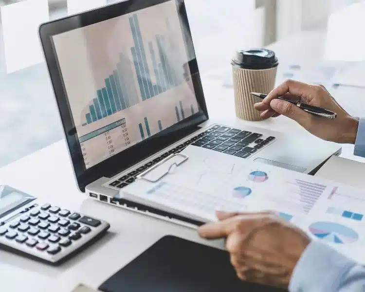 Financial charts and a calculator at a laptop