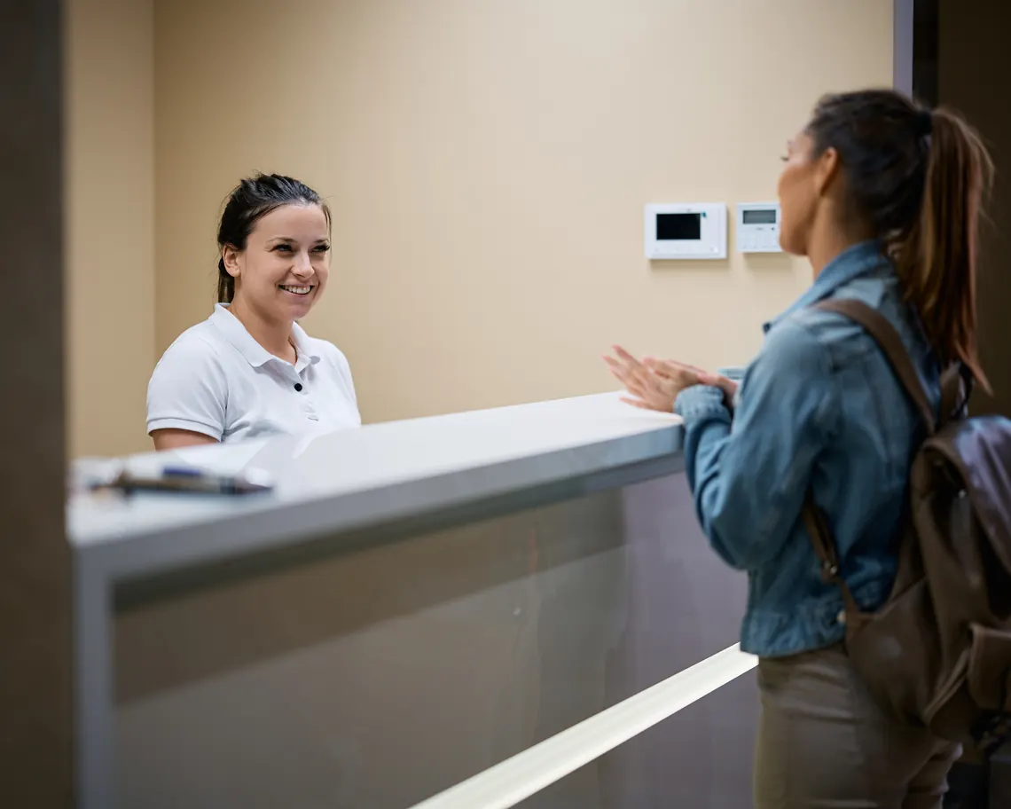 Patient checking in at a medical office front desk Patient checking in at a medical office front desk