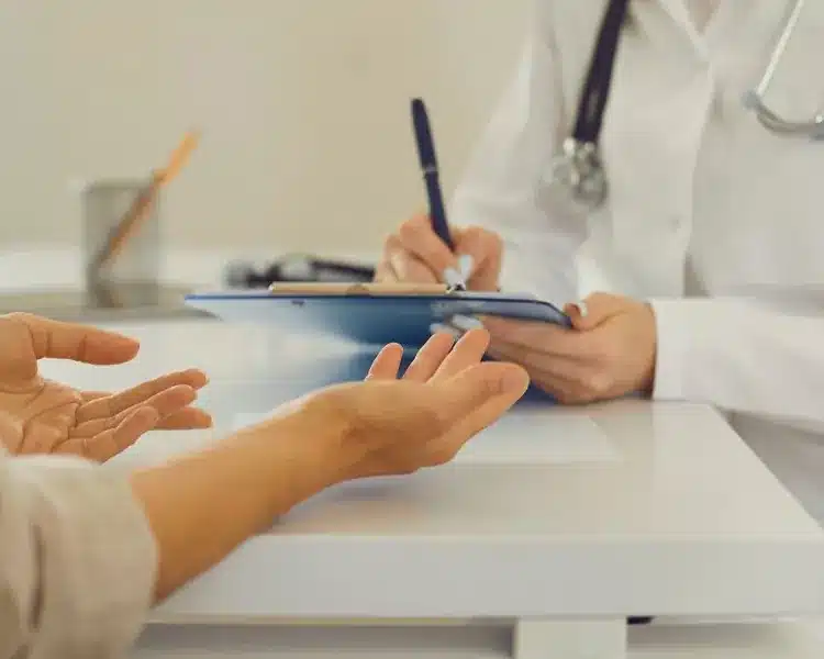 Patient talking with a doctor at a desk Patient talking with a doctor at a desk