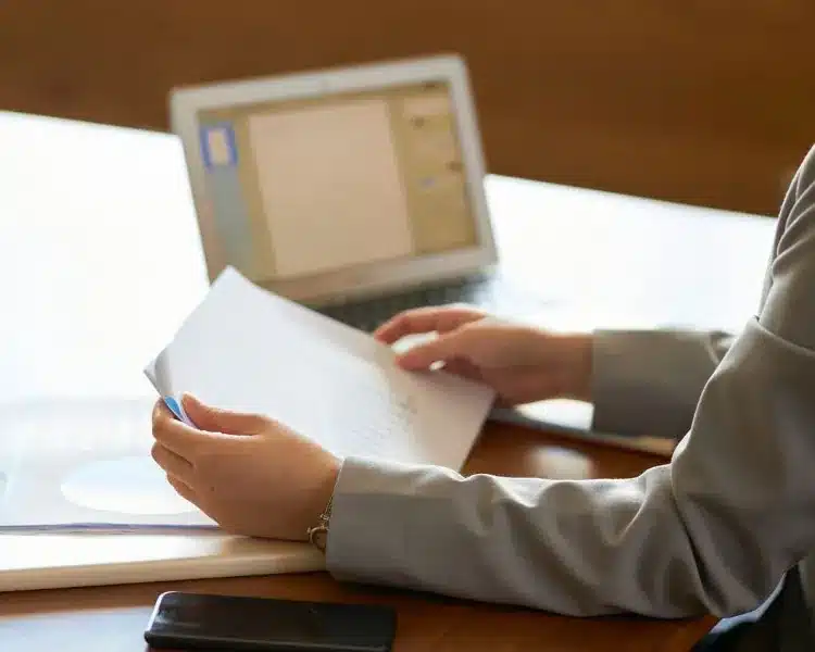 Professional reviewing documents at a laptop