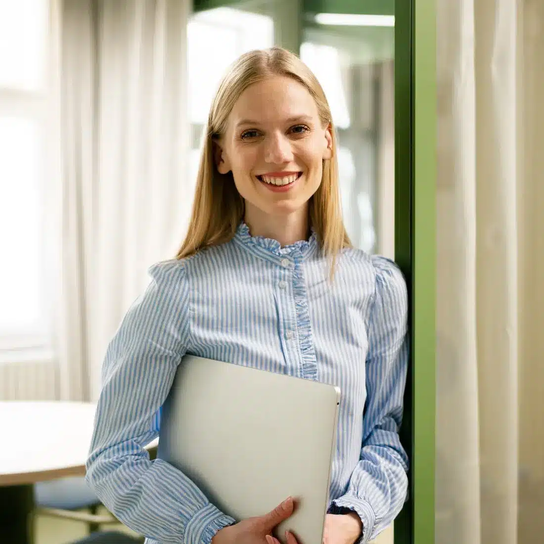 Smiling account manager holding a laptop in a bright office