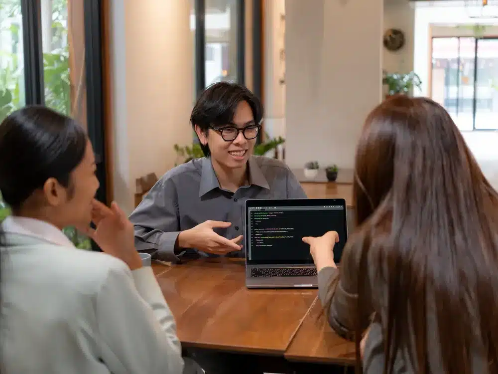 Three professionals collaborating around a laptop during an AI consulting working session