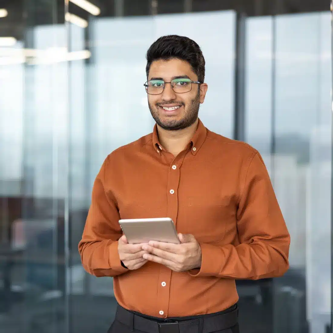 Technical marketer in an orange shirt holding a tablet in an office