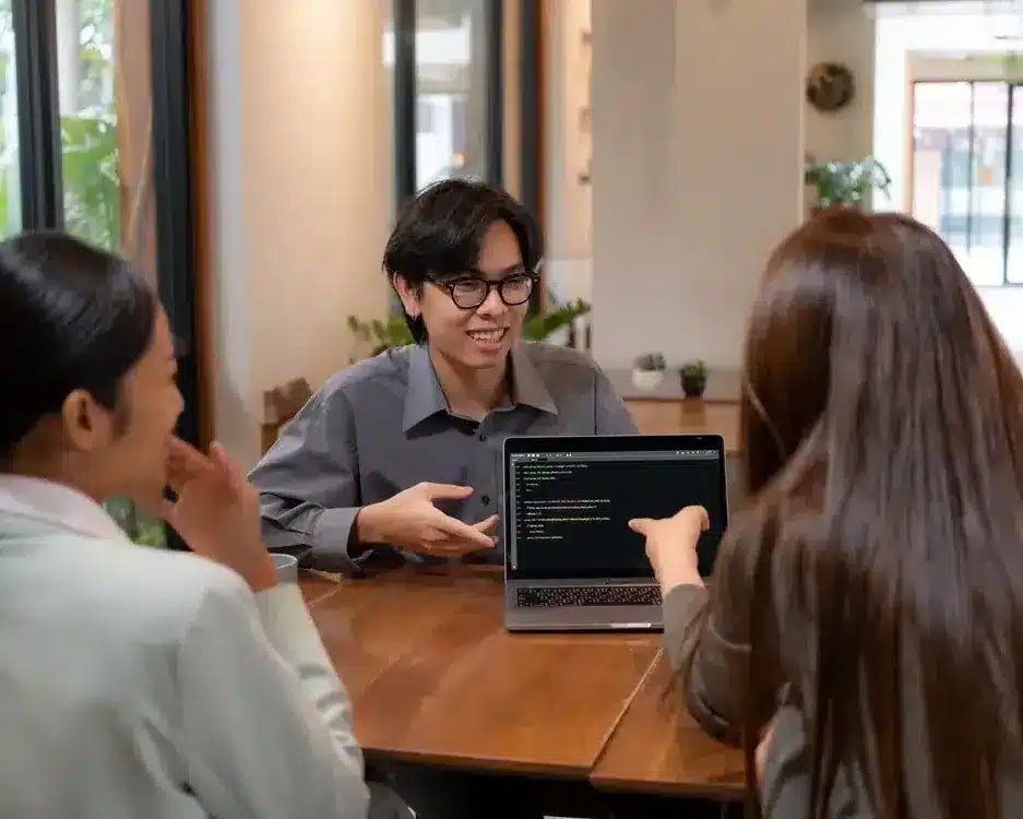 Three professionals collaborating at a laptop