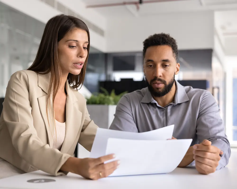 Two attorneys reviewing printed legal documents at a desk
